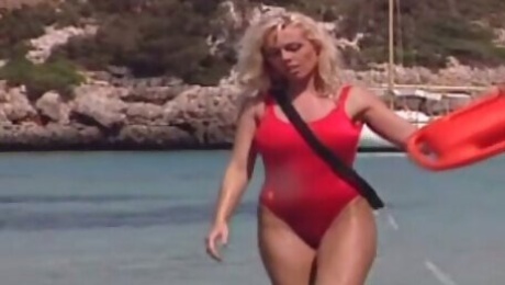 Saucy blond haired MILF in red swim suit performs steamy solo on sandy beach